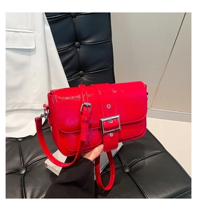 Détail de sac à bandoulière en cuir verni rouge brillant avec une boucle argentée