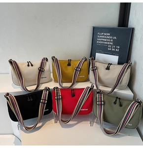 Detail of colorful canvas crossbody bags with striped straps and OOMTAO logo branding