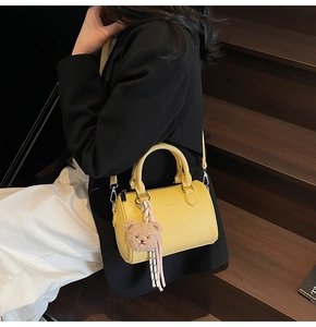 Chic yellow lychee leather cylinder bag styled with plush bear charm and striped ribbon
