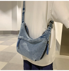 Detail shot of light blue denim crescent crossbody bag with adjustable wide strap