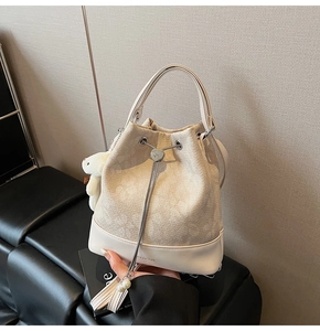 Detail view of cream tweed bucket bag with heart metal buckle and pearl charm