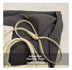 Detail of adjustable thin strap with gold metal buckle on white faux crocodile handbag