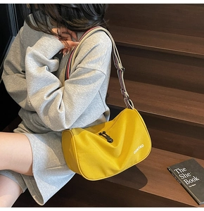 Vibrant yellow crescent crossbody bag with colorful striped wide strap and nylon texture