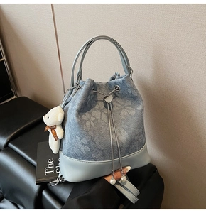 Detail of floral denim bucket bag with metal chain drawstring and cute bear charm