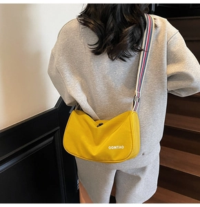 Detail of yellow nylon crescent bag with striped wide strap and white letter print