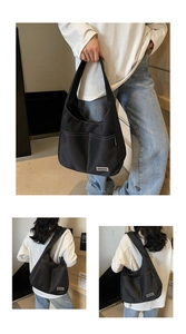 Detail of black canvas tote bag showing white contrast stitching and the outer pocket design
