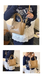 Detail view of khaki crocodile pattern bucket bag with a heart pendant and strap