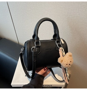 Detail of black pebbled leather boston bag with bear charm and chic shoulder strap