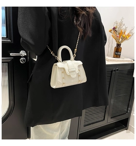 Detailansicht der weißen Leder-Mini-Trapeztasche mit goldener Kette und Nieten