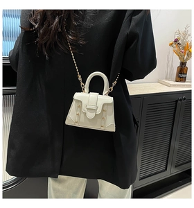 Mini borsa a mano crema con borchie dorate e catena metallica, dettaglio della modella
