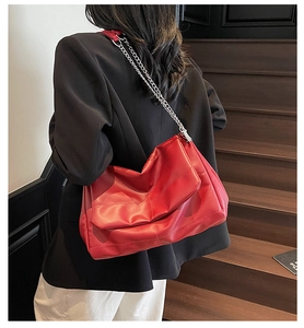 Detail of red quilted leather crossbody bag with silver chain strap on a model