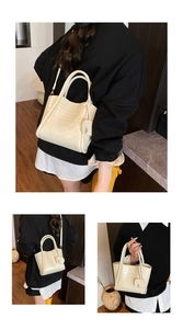 Detail view of beige crocodile embossed bucket bag with heart pendant and strap