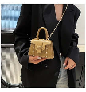 Detailansicht der khakifarbenen Mini-Umhängetasche mit Goldkette und Nieten an der Seite