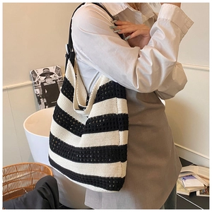 Detailed view of black and white woven tote bag with a premium black leather shoulder strap