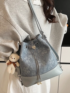Light blue floral bucket bag with drawstring and cute bear charm shown on shoulder