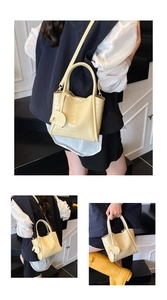 Detail view of yellow crocodile embossed leather bucket bag with cute elephant charm