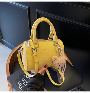 Detail of yellow lychee grain cylinder bag with plush bear and ribbon accessory