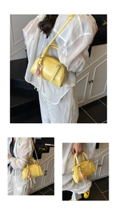 Détail du sac à main jaune en cuir verni avec breloque cœur rose et sangle tressée