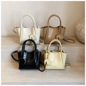 Close-up of four luxury bucket bags in cream, brown, black, and yellow with croc texture