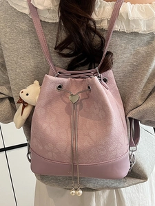 Pink drawstring bucket backpack with heart buckle, chain straps, and bear charm accessory