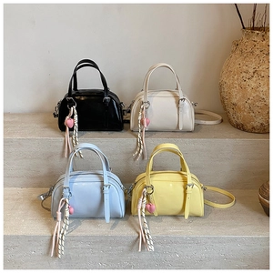 Sélection de quatre mini sacs bowling chic aux tons pastels sur un support en pierre