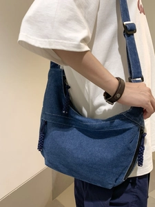 Minimalist navy denim crescent crossbody bag with white stitching and woven zipper pull