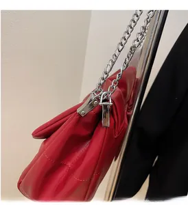 Detailed view of silver chain strap and quilted red leather texture on the handbag