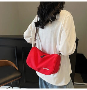 Detail of red canvas dumpling bag showing white OOMTAO logo and colorful woven strap