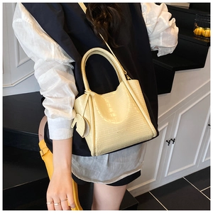 Detail of yellow crocodile pattern bucket bag with cute elephant charm and strap