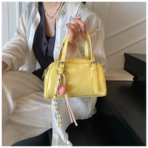 Détail du sac à main en cuir verni jaune pâle avec pendentif cœur rose et boucle argent