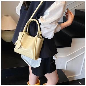 Detail shot of pale yellow crocodile texture bucket bag with cute elephant charm accessory