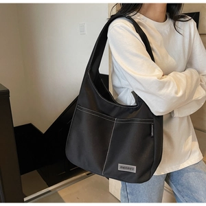 Detail of black large capacity tote bag with white contrast stitching and canvas texture