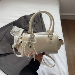 Close-up of beige Boston bag with pearl bow charm and elegant heart pendant decoration