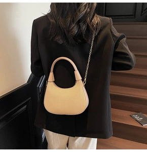 Detail der beigen Hobo-Tasche mit Webstruktur, getragen von Model auf Holztreppen