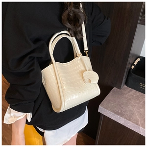 Detail of cream white faux crocodile leather bucket bag with heart pendant and shoulder strap
