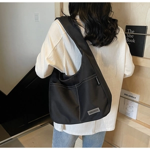 Detail of the black tote bag with white contrast stitching and Merrey metallic logo