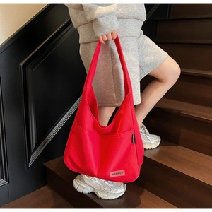Detailed view of a red large capacity canvas tote bag with side pocket and logo label