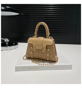 Dettaglio mini borsa kaki con rivetti a sfera dorati e tracolla a catena metallica