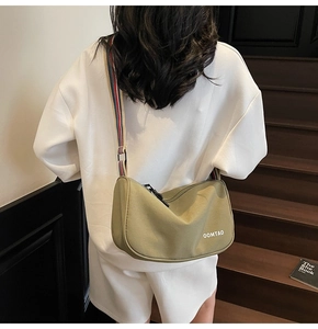 Olive green canvas half-moon bag with colorful striped shoulder strap and logo print