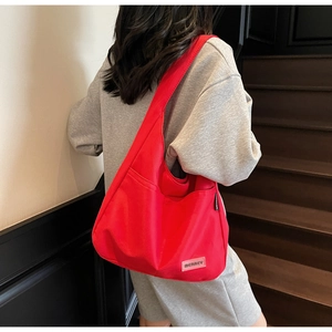 Detail view of the vibrant red tote bag featuring an outer pocket and side brand label
