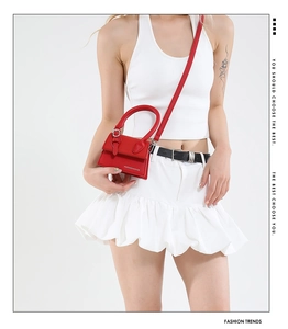 Détail du sac bandoulière rouge avec motif litchi, fermoir et poignée supérieure