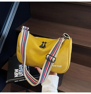 Detail view of yellow canvas dumpling bag with striped strap and OMTAO logo