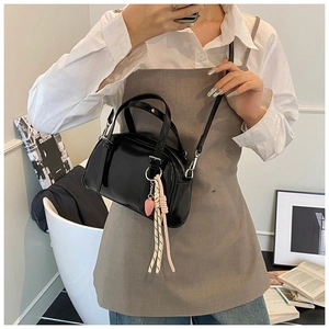 Détail d'un sac à main en cuir verni noir avec charm fraise et pompon tressé élégant
