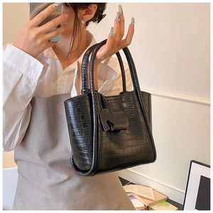 Detail of black crocodile texture handbag with cute elephant charm and twin handles