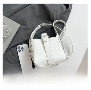 Mini sac seau blanc avec rivets argentés comparé à un smartphone pour la taille