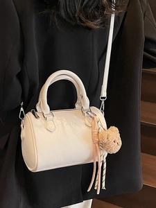 White lychee leather cylinder bag with bear charm and adjustable shoulder strap