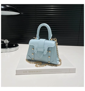 Dettaglio della mini borsa azzurra con borchie dorate e catena a sfere dorata