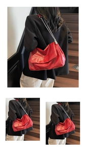 Detailed view of red cloud bag with silver chain strap and soft pleated faux leather texture