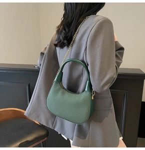 Detail der dunkelgrünen gewebten Hobo-Tasche mit goldener Kette an der Schulter