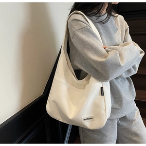 Close-up of minimalist white canvas tote bag with branded woven labels on soft fabric